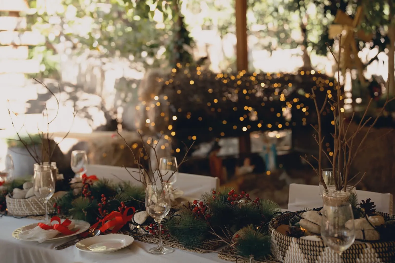 An outdoor table set with festive decorations and warm lights.