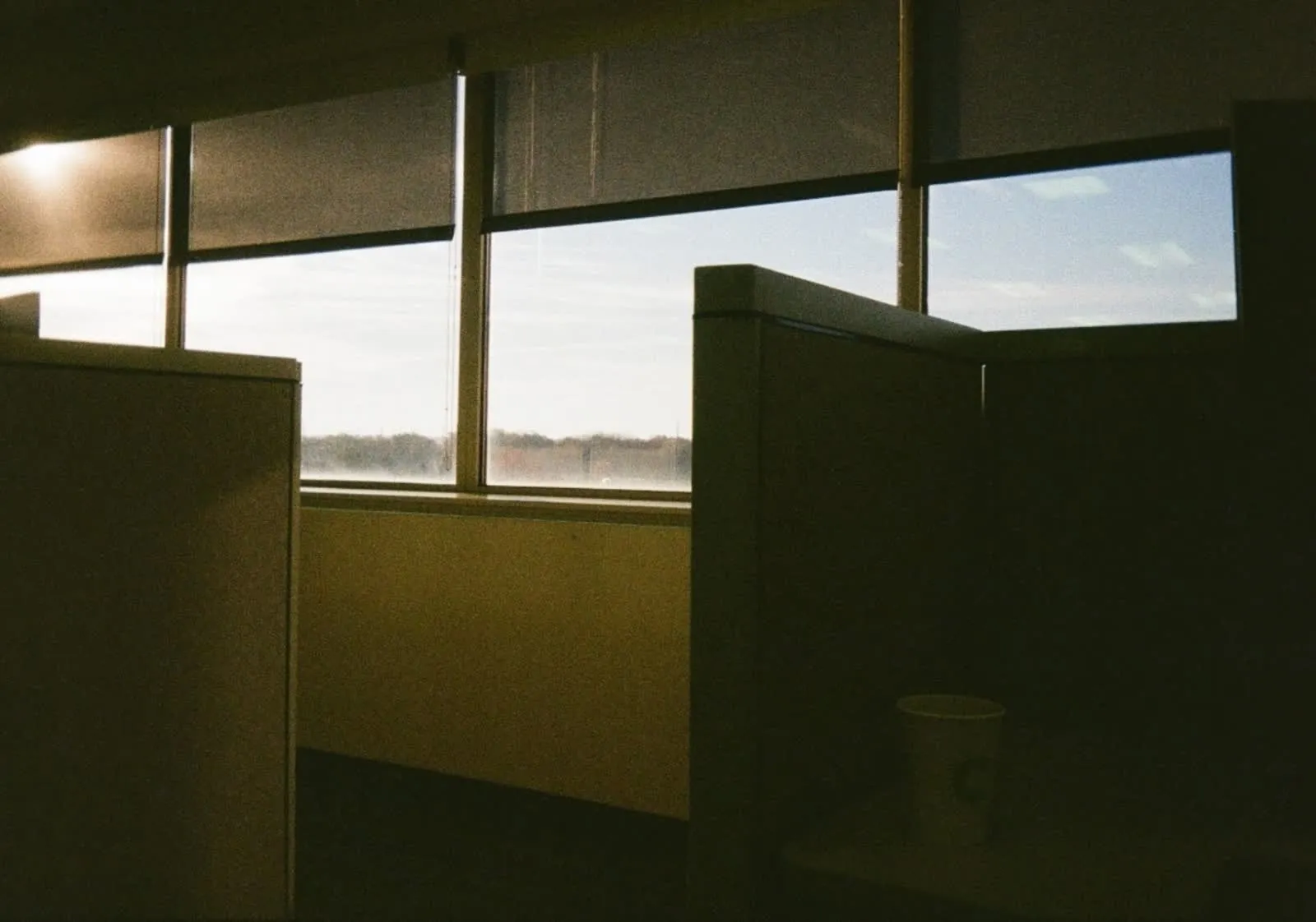 An empty office cubicle beside a window at first light.
